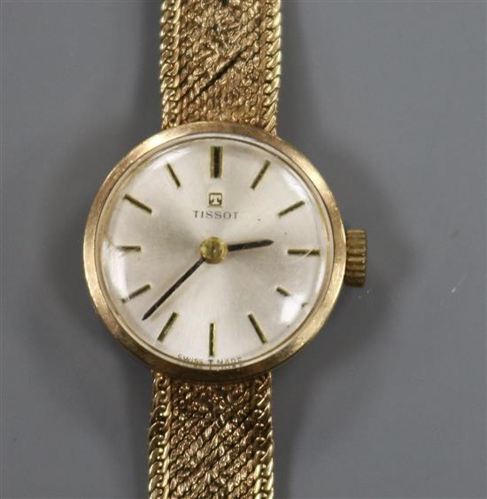 A ladys 9ct gold Tissot manual wind wrist watch on a textured 9ct gold bracelet.